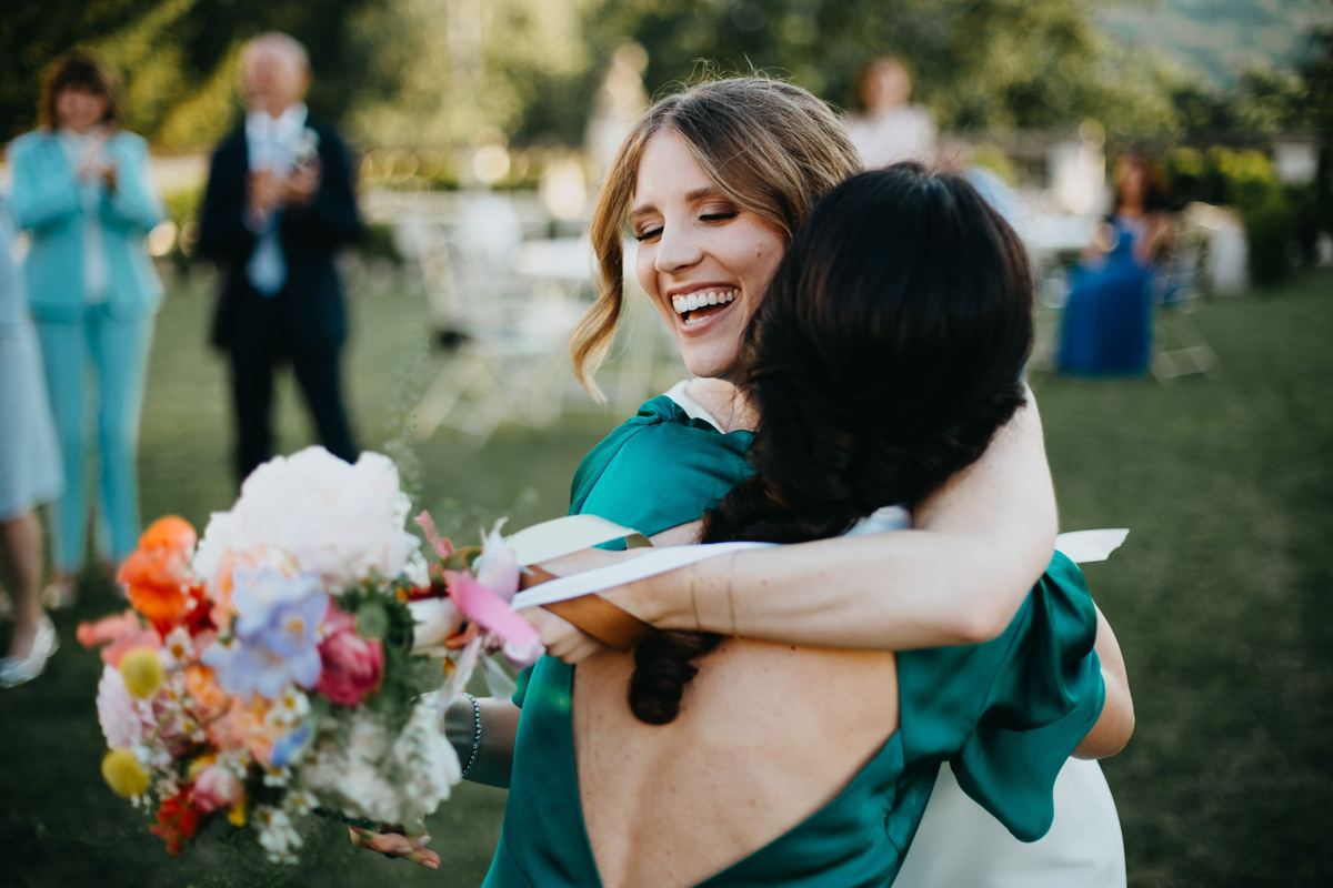 Sposa ride abbracciando un'amica dopo il lancio del bouquet