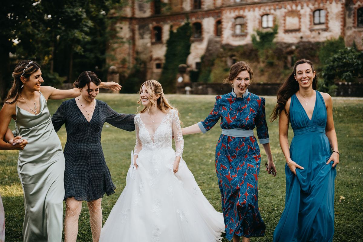 Sposa cammina nel prato ridendo con le amiche