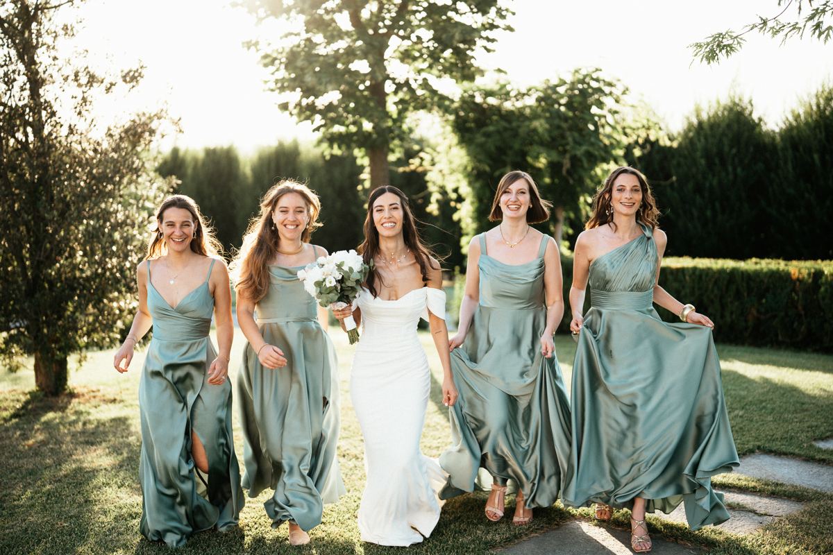 Sposa che cammina in giardino insieme alle damigelle